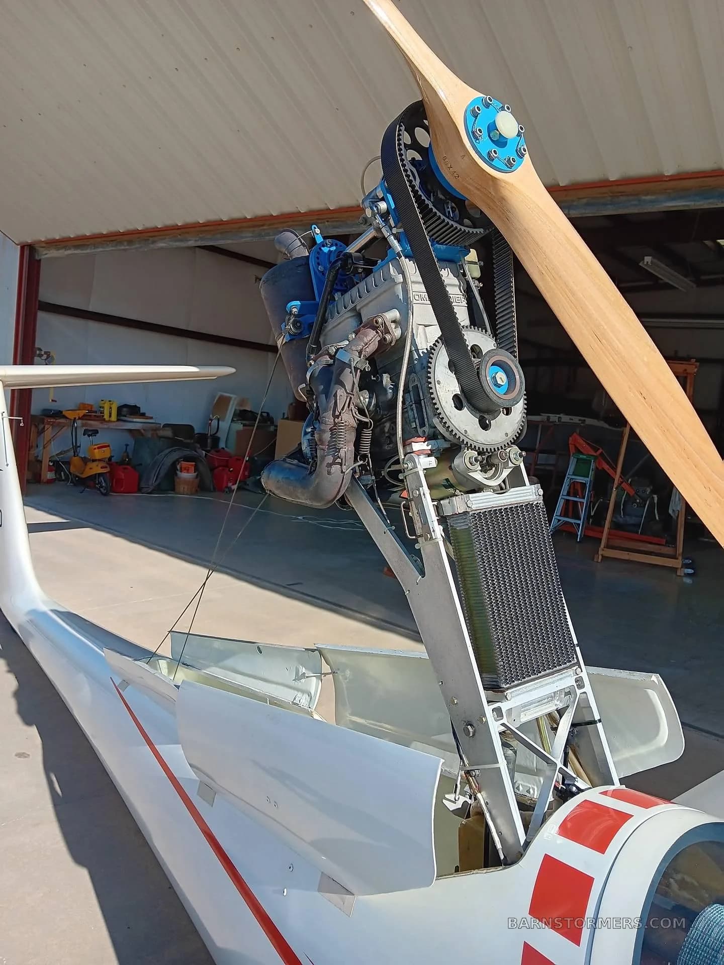 A close-up view of the deployed retractable engine and wooden propeller of a Grob G 103 glider, showing mechanical components.