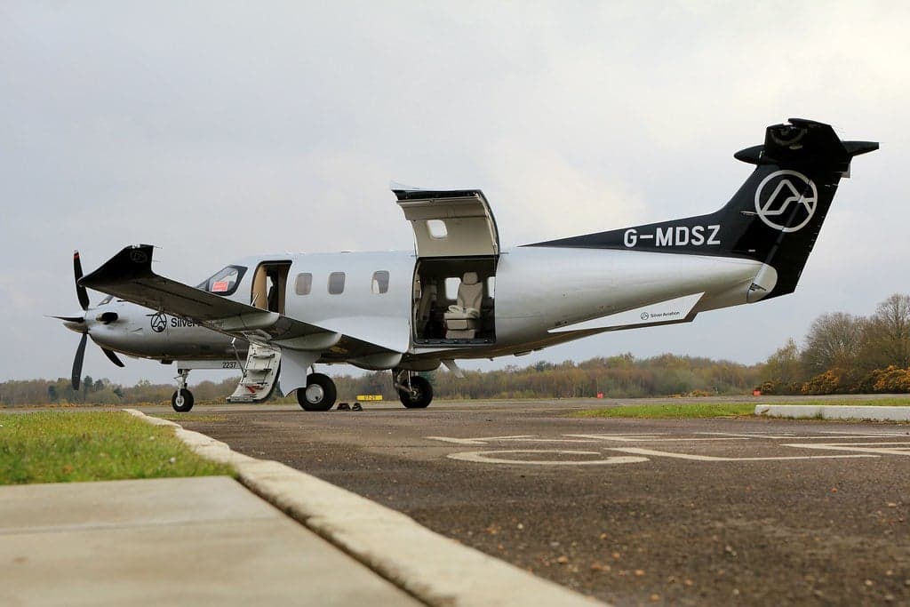 A Pilatus PC-12 aircraft with registration G-MDSZ parked on the tarmac with the door open.