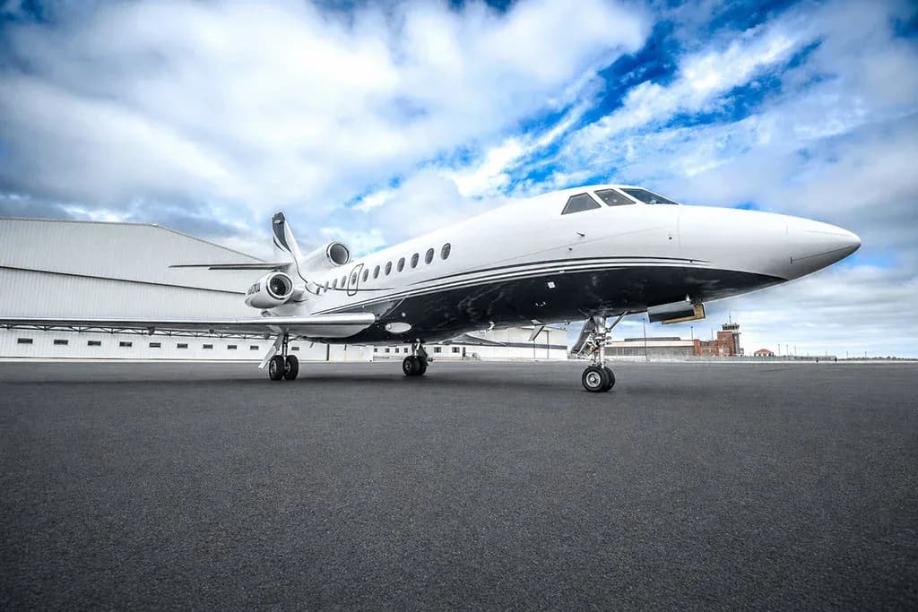 A front low-angle view of the Dassault Falcon 900EX business jet, registration N900KU, parked on a tarmac.