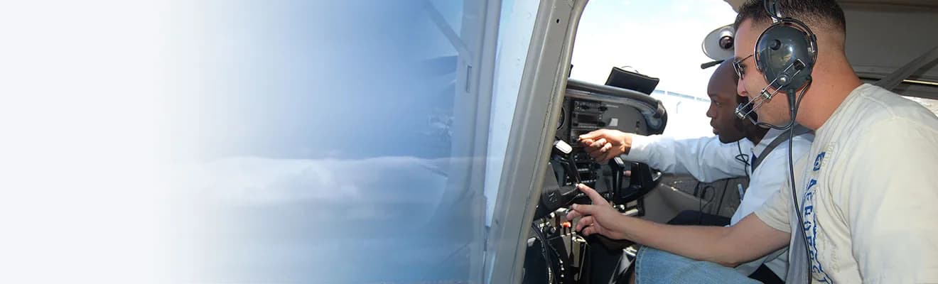 Two men in the cockpit of an aircraft, one pointing at the instrument panel.