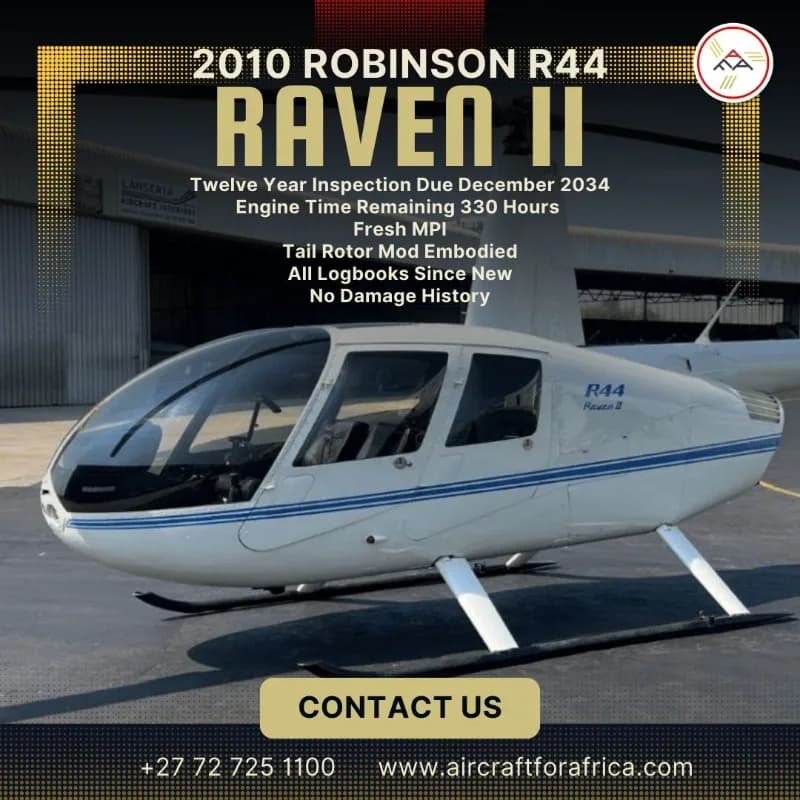 A white Robinson R44 Raven II helicopter with blue stripes, viewed from the front-right, parked on an asphalt surface with a hangar in the background.