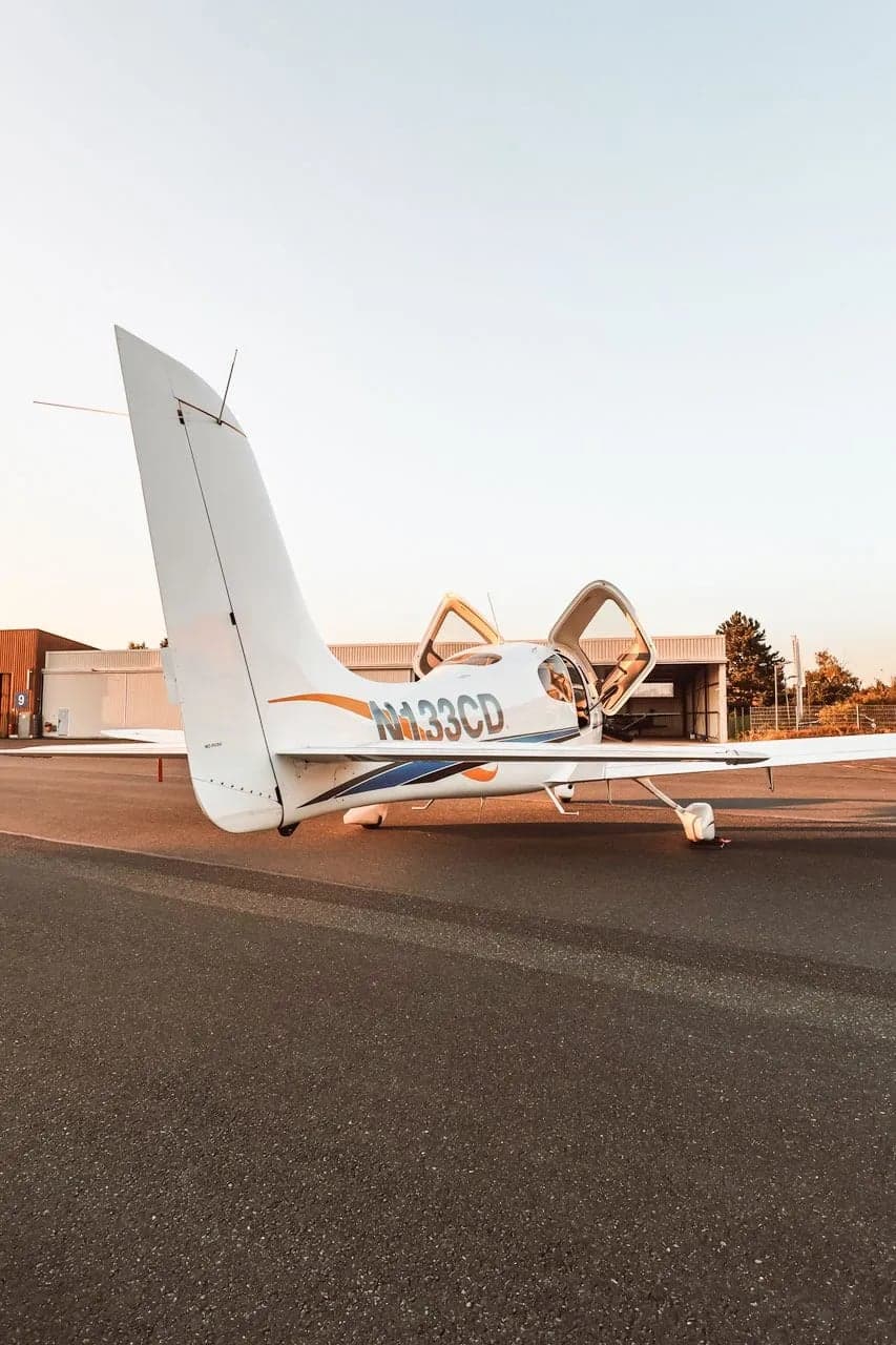 Cirrus SR22 aircraft N133CD parked on the tarmac, rear side view with doors open.