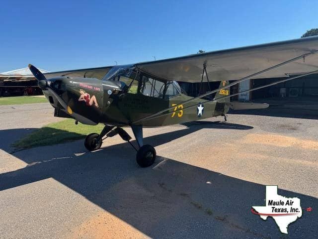 A side view of a green Maule Air Texas aircraft with a pin-up girl painted on the nose.
