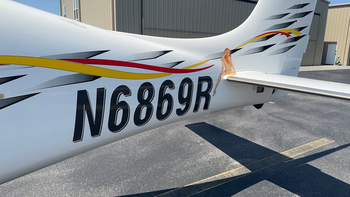 Close-up of the tail of a Cirrus aircraft showing the registration number N6869R and custom graphics.