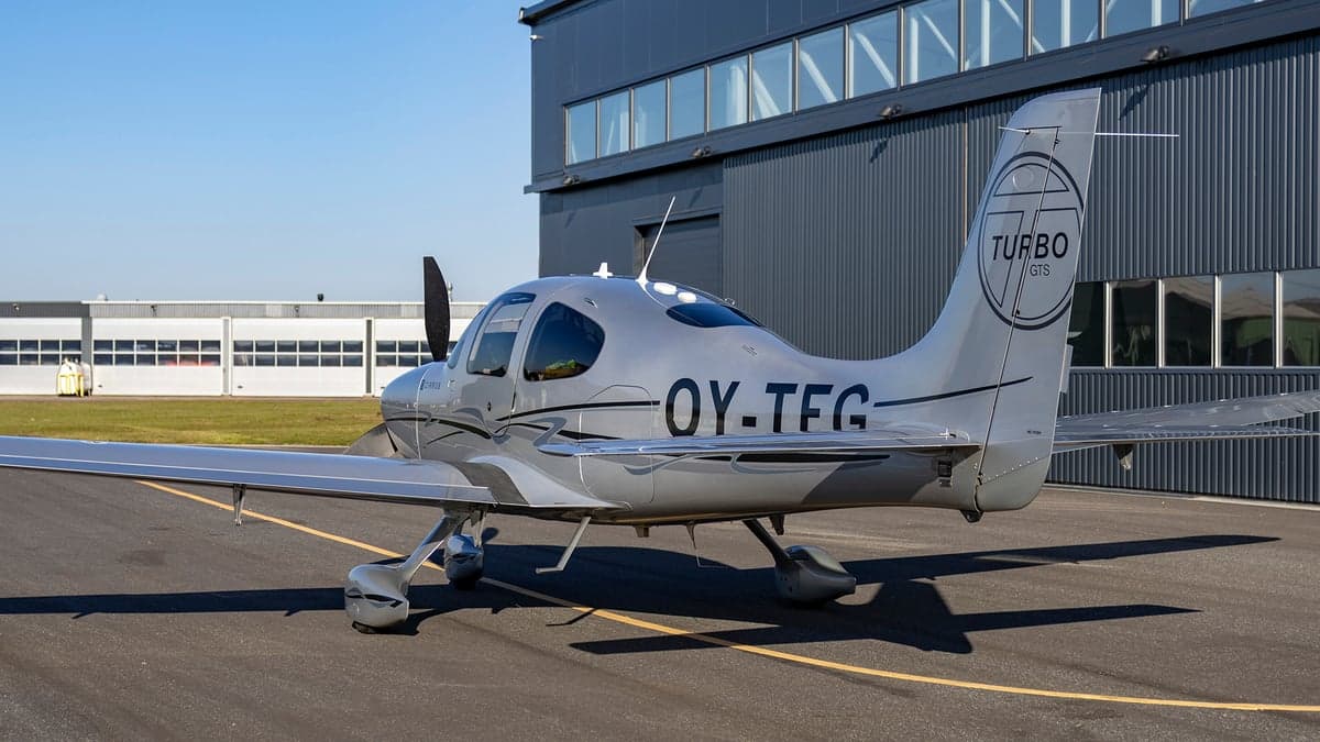 Rear side view of the silver Cirrus OY-TEG on the tarmac.
