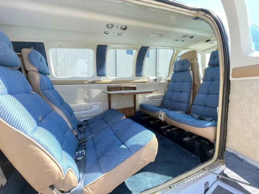 View of the aircraft cabin with blue patterned seats and a small fold-out table.
