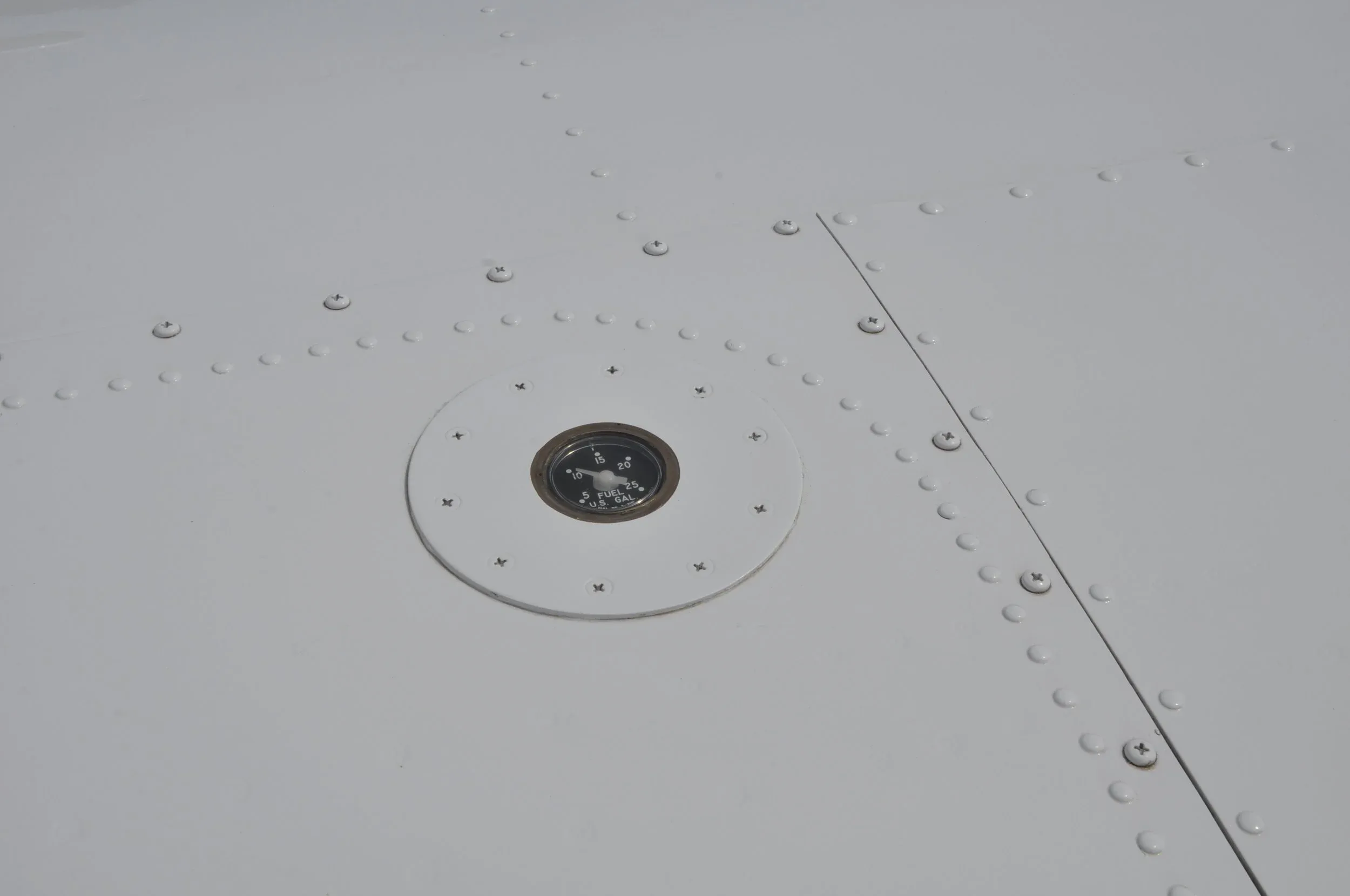 A close-up of a fuel gauge embedded in the white aircraft wing.