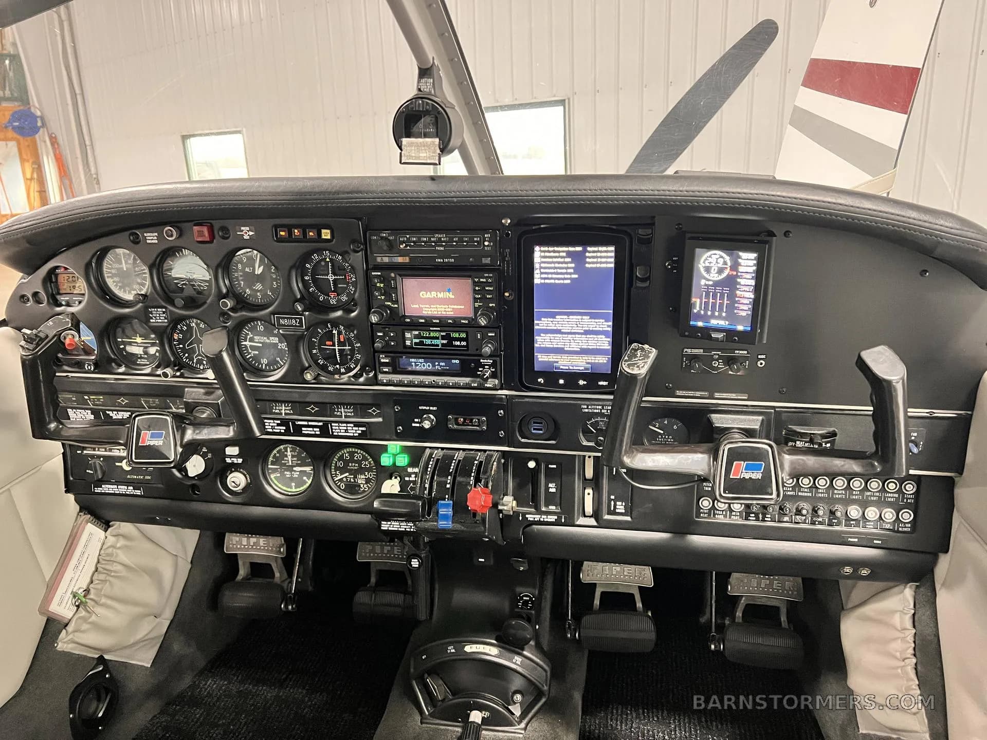 The cockpit of a small aircraft, featuring a detailed instrument panel with analog gauges and modern digital displays.