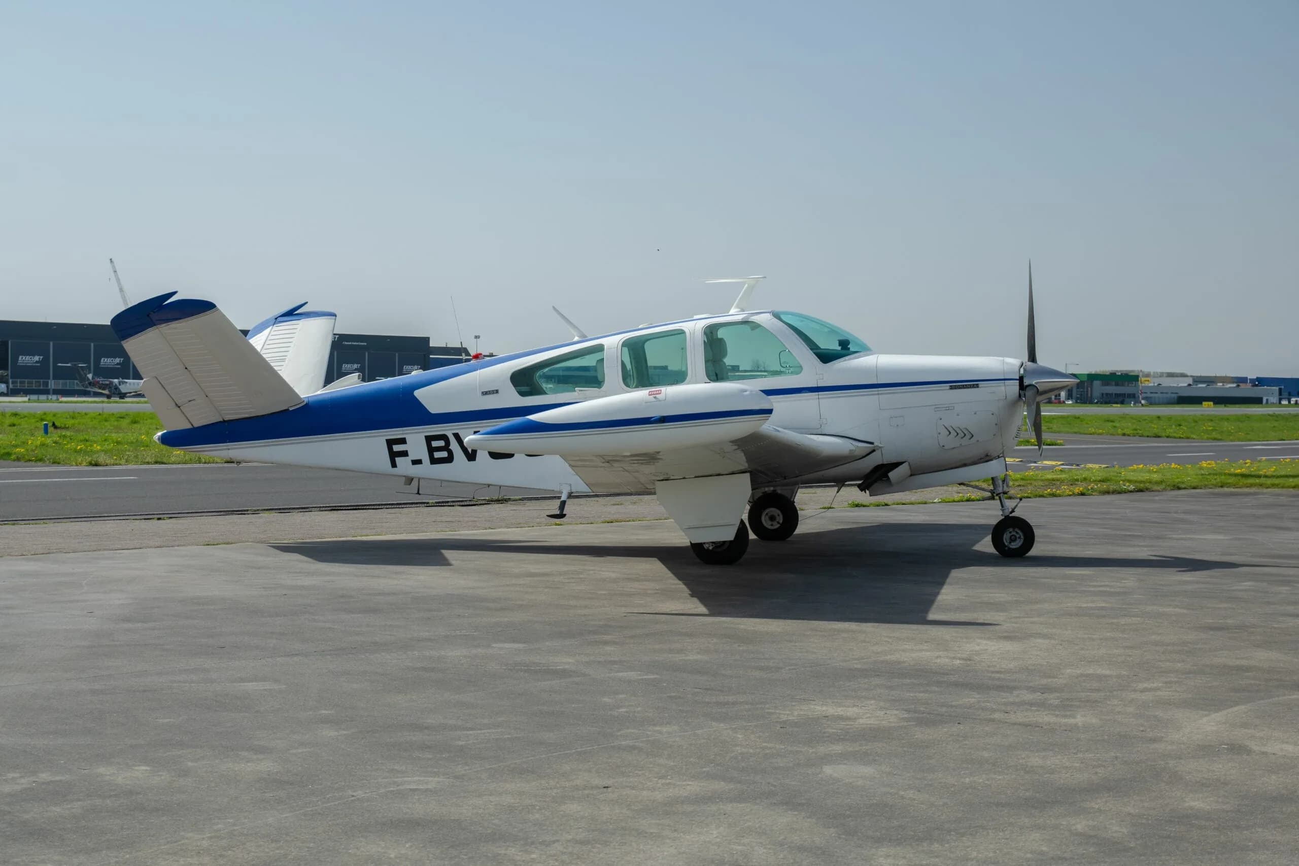 A white and blue single-engine aircraft, registration F-BVOS, sits on the tarmac.