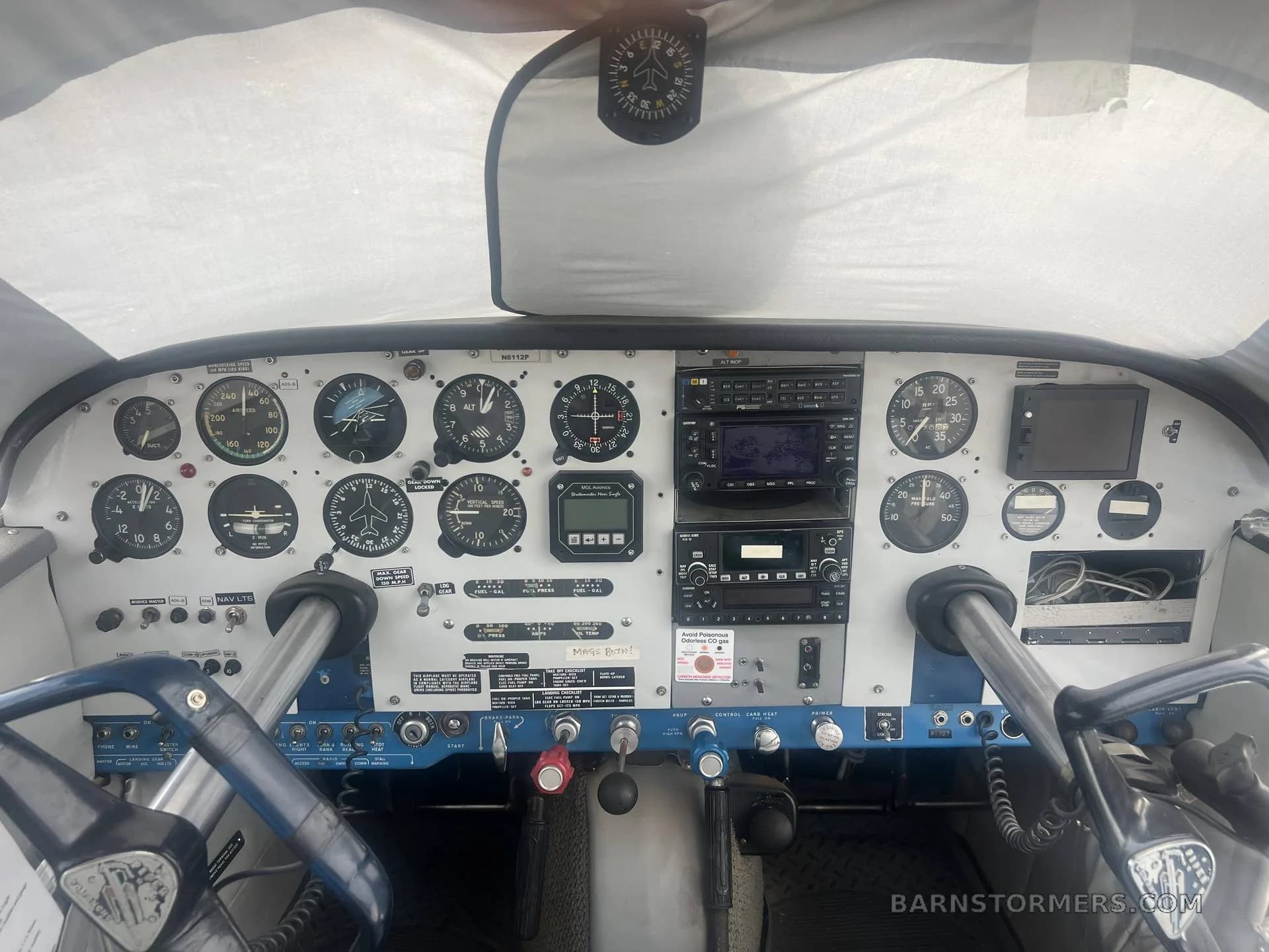 The cockpit of a small aircraft, showing the instrument panel with various gauges, radios, and control yokes.