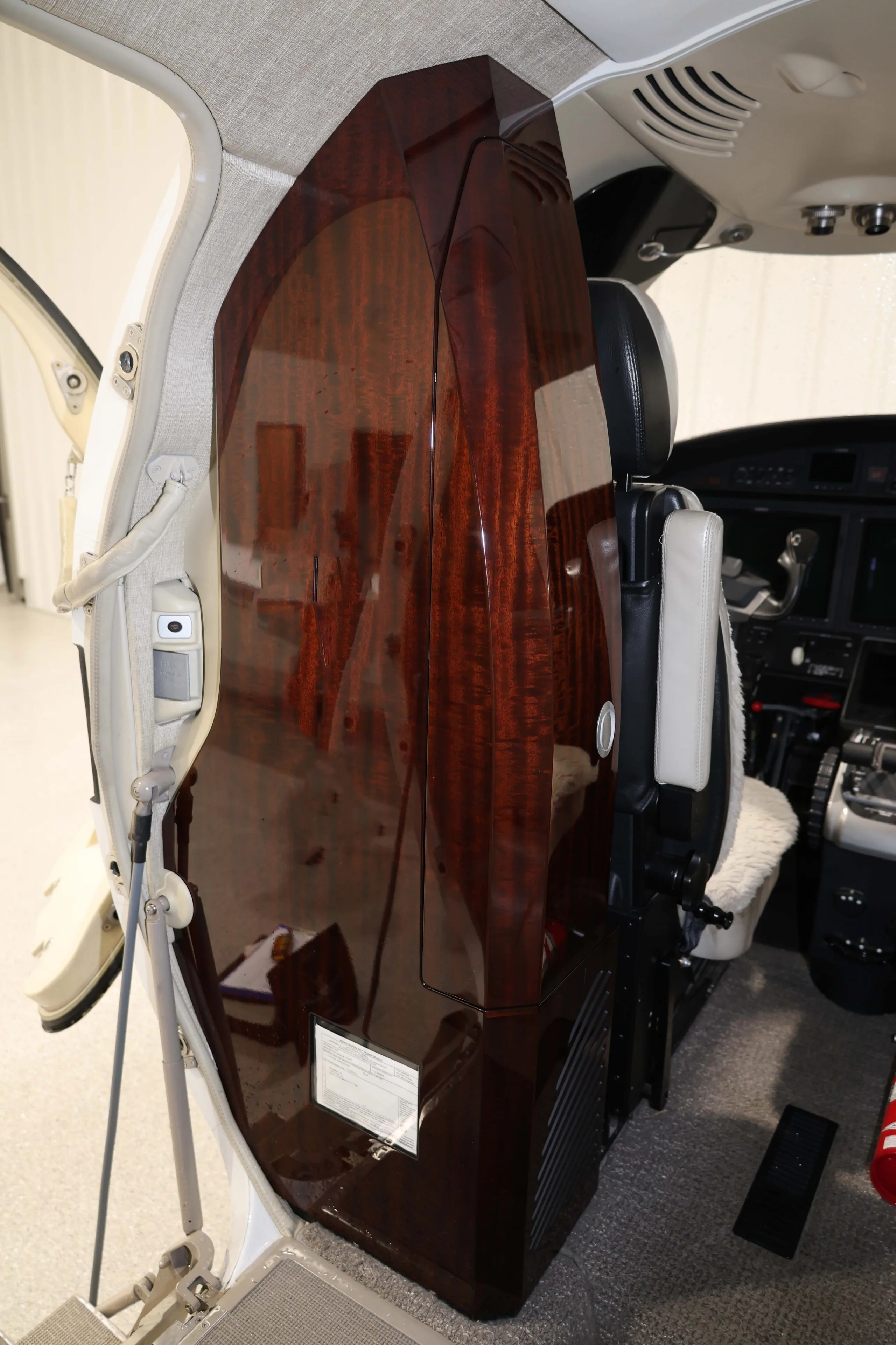 A view from the cabin looking towards the cockpit, showing a dark wood cabinet and the open main cabin door.