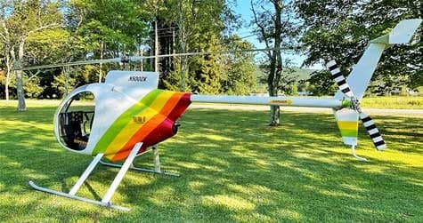 A side view of the N500ZK helicopter with a rainbow paint scheme on the tail.