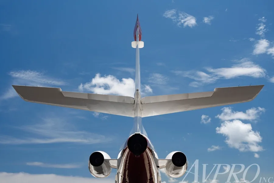 Rear view of a white and red Dassault Falcon 900EX showing its T-tail and two rear engines.