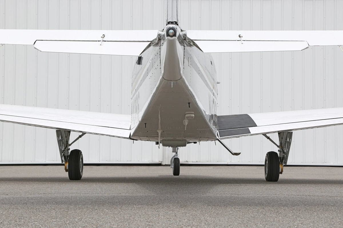 Close-up rear view of a white and silver Beechcraft Bonanza on the tarmac.
