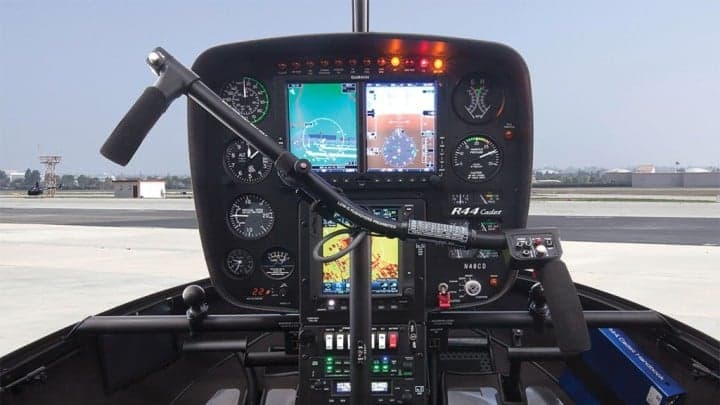 Red Robinson R44 helicopter flying near an airport control tower.