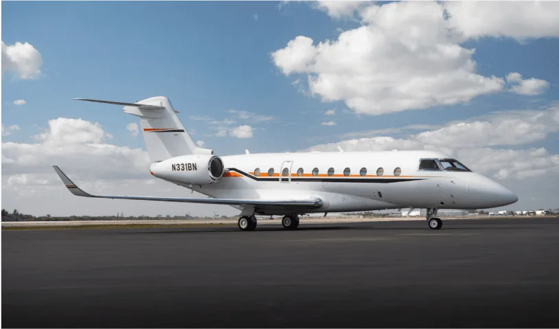 A white business jet with orange and black stripes, registration N331BN, parked on an airfield under a partly cloudy sky.