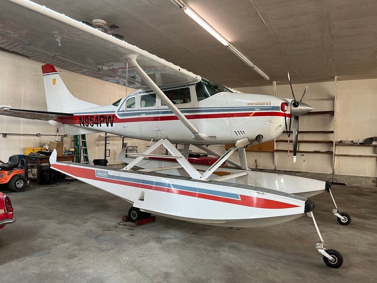 A Cessna Stationair 6 II floatplane with US registration N954PW is parked in a hangar.