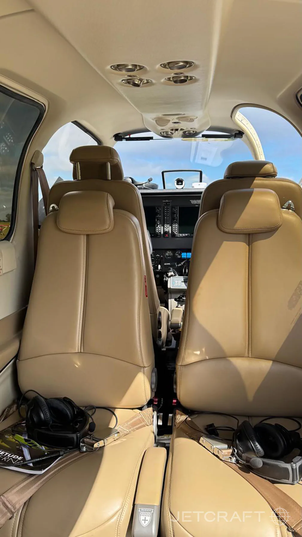The aircraft's interior features tan leather seats and a view of the cockpit.