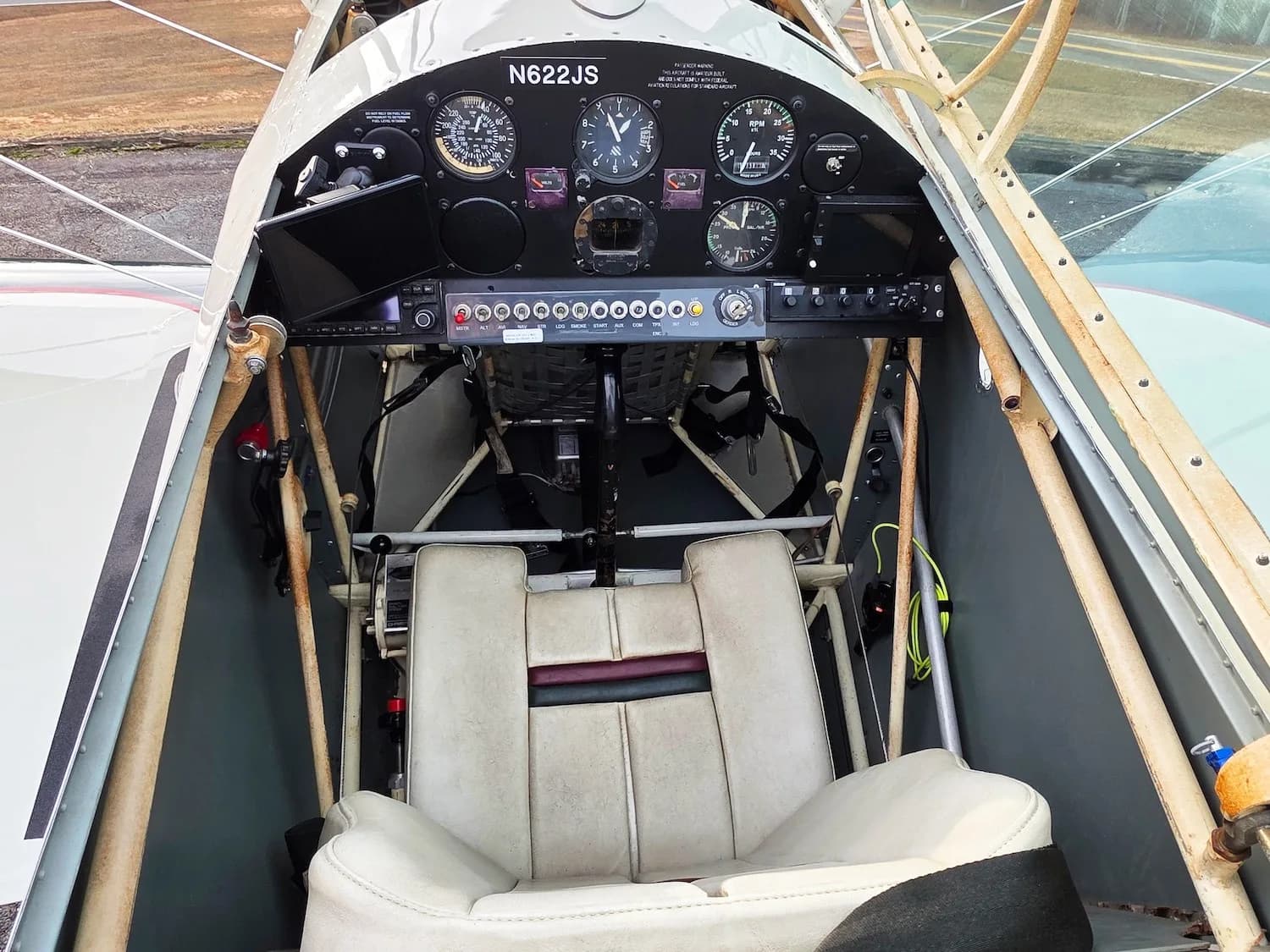 An overhead view of the biplane's cockpit, showing the instrument panel and a single cream-colored seat.