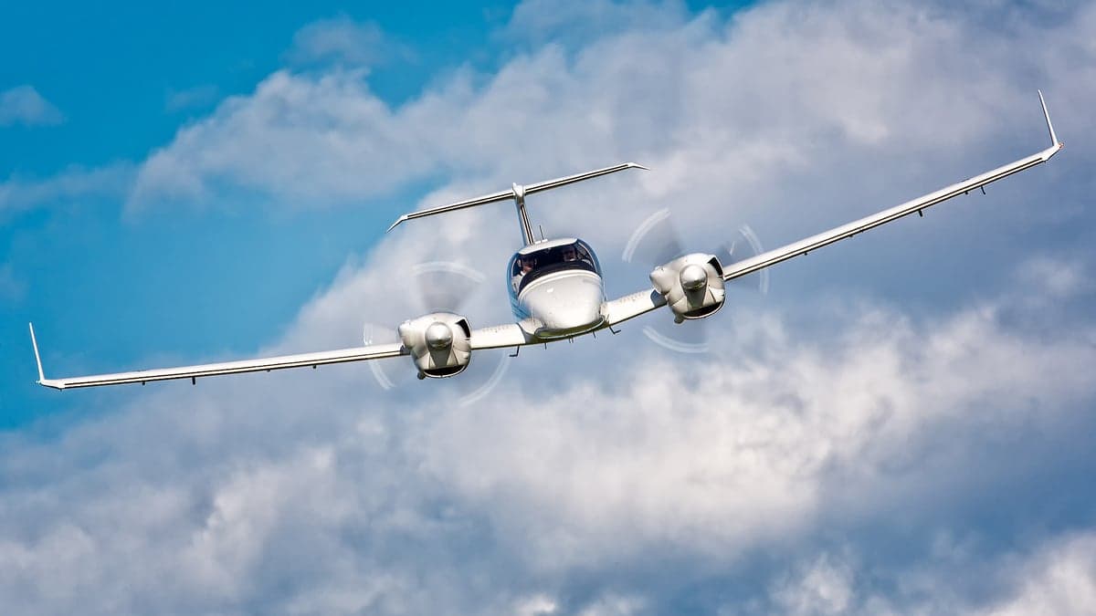 Front view of a Diamond DA62 aircraft in flight against a cloudy sky.