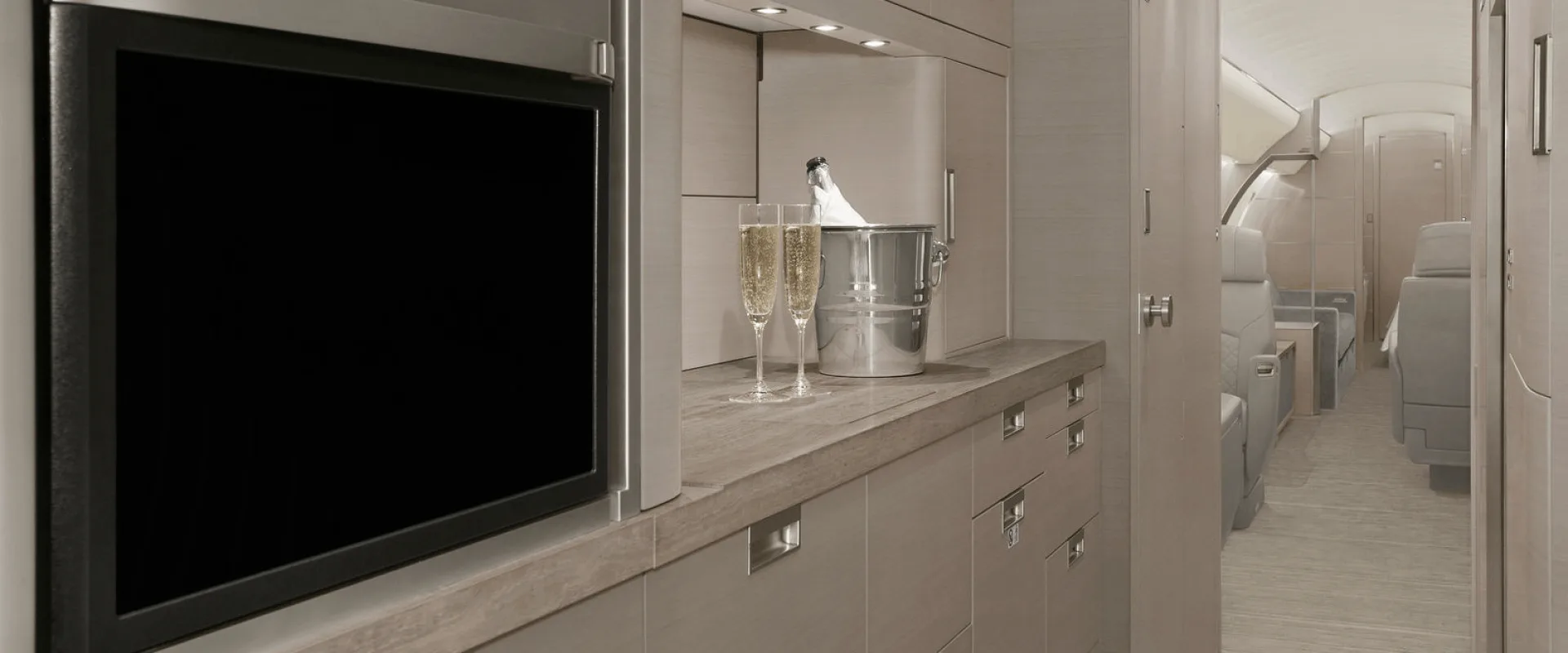 Aircraft cabin with champagne and glasses on a counter.