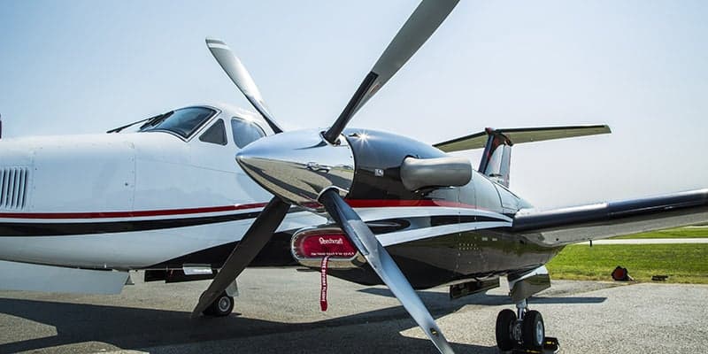A close-up view of the polished propeller and engine nacelle of a white and black King Air 350i.