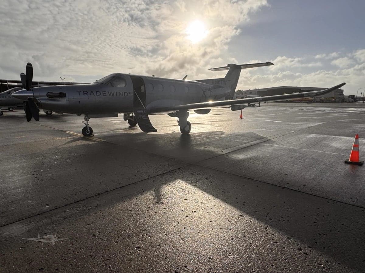 A Tradewind PC-12 aircraft, registration N881TW, parked on the tarmac with the sun shining behind it.