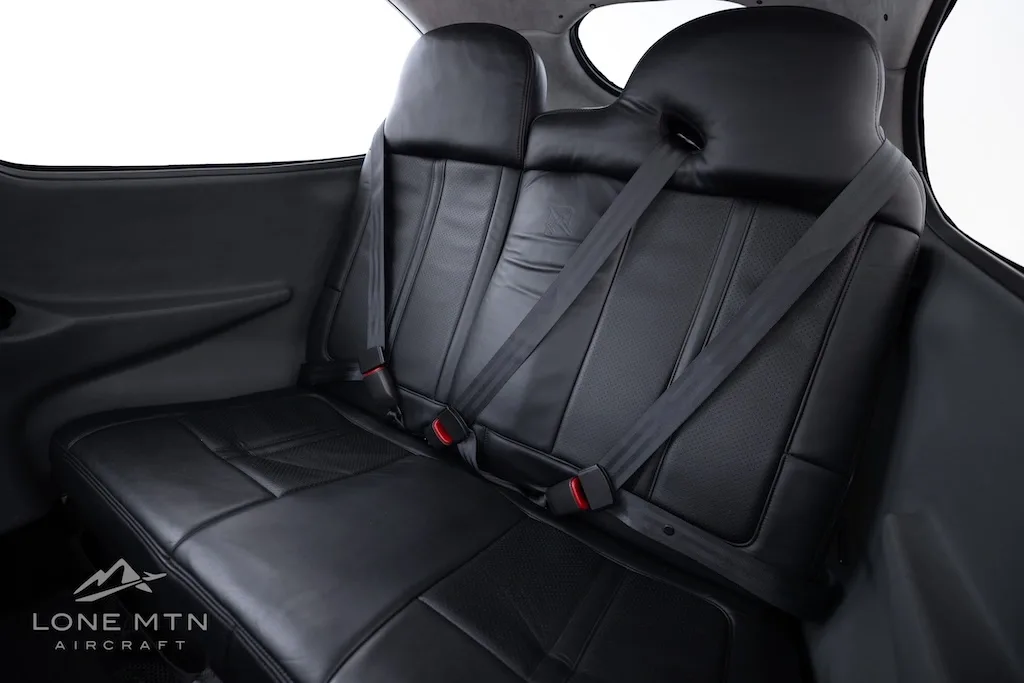 The black leather rear seats of the aircraft cabin with seatbelts visible.