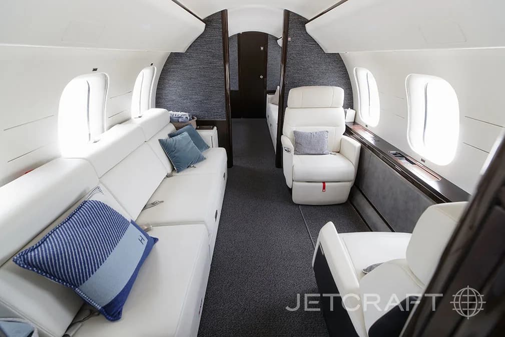 The aft cabin of a Bombardier Global 7500 with a long white sofa and a single white armchair.