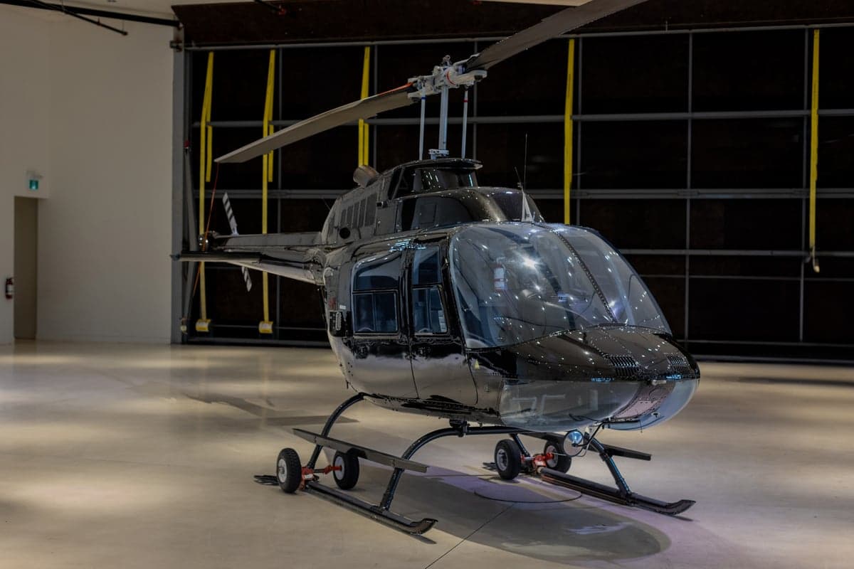 A black helicopter is parked in a hangar, viewed from above.