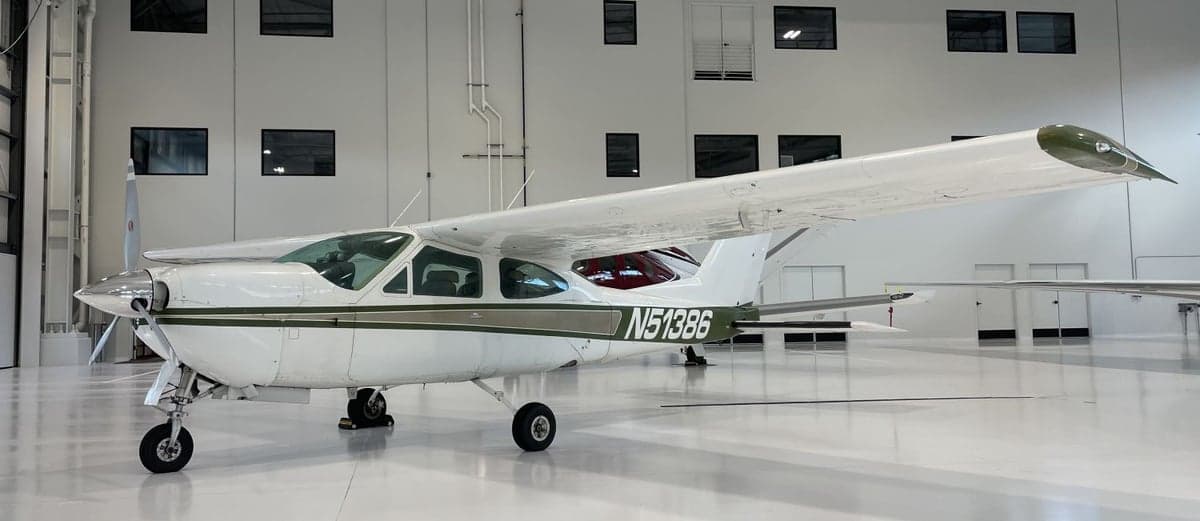 A white and green Cessna Cardinal RG II, registration N51386, is parked inside a hangar.