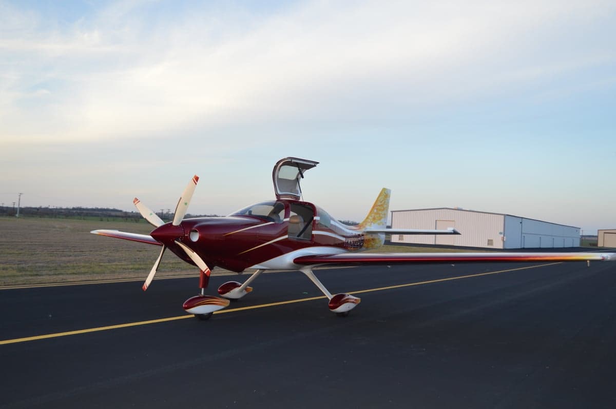 The aircraft is parked on the tarmac with its gull-wing door open.
