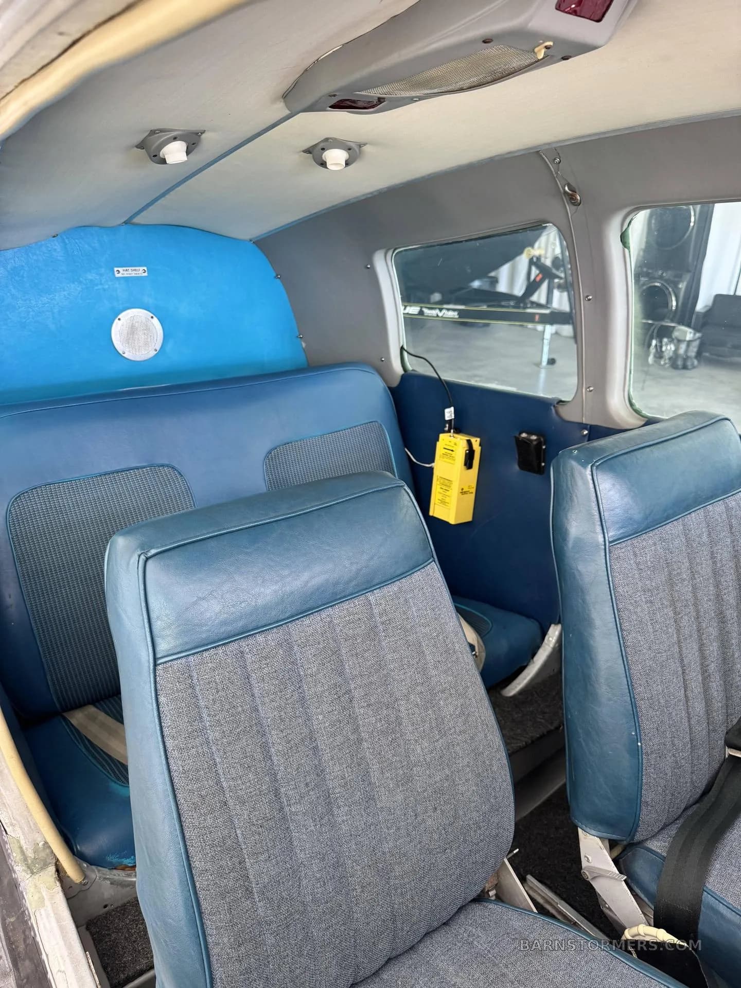 The interior cabin of a small aircraft, featuring blue and grey fabric seats and blue side panels.