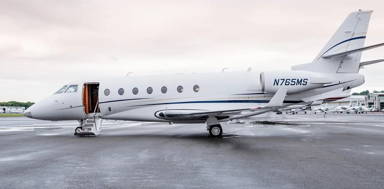 Side view of a white aircraft with blue and gold accents, registration N765MS, with the door open and stairs extended.