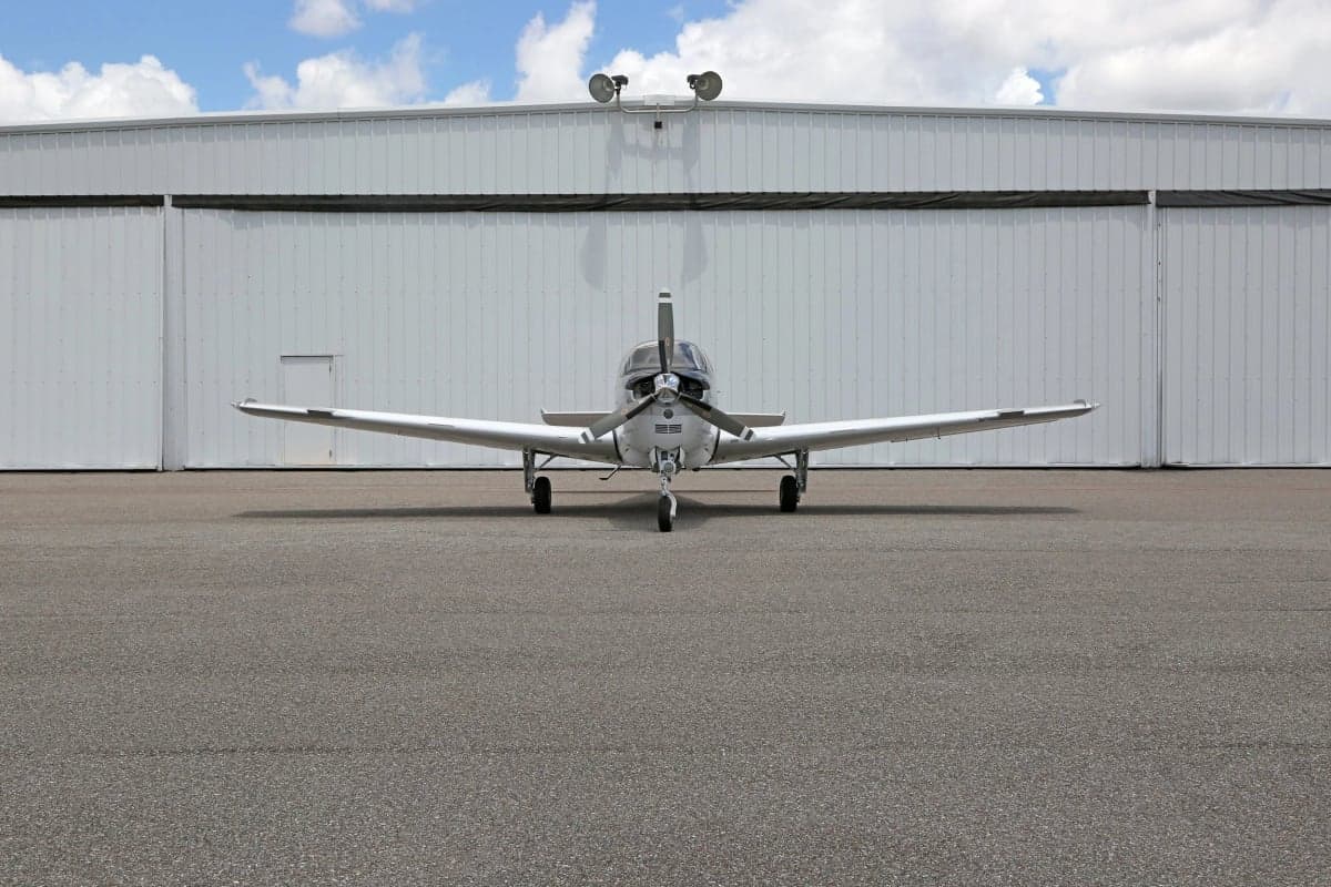 Front view of a Beechcraft Bonanza aircraft parked in front of a hangar.