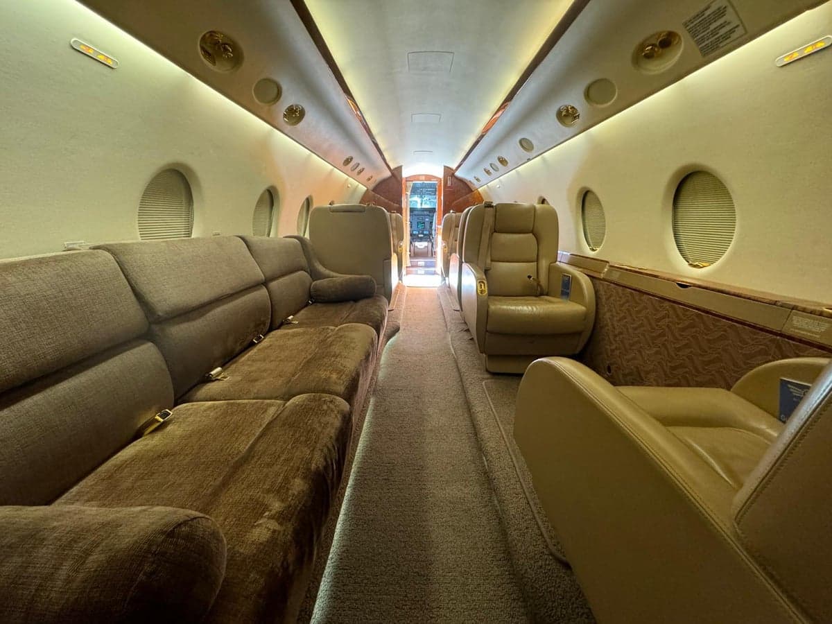 A view down the center aisle of the aircraft cabin, showing seating.