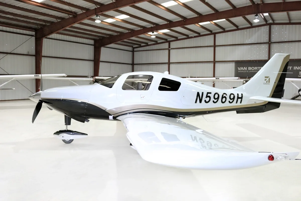 A side view of the white and black single-engine aircraft, N5969H, with its tail visible, in a hangar.