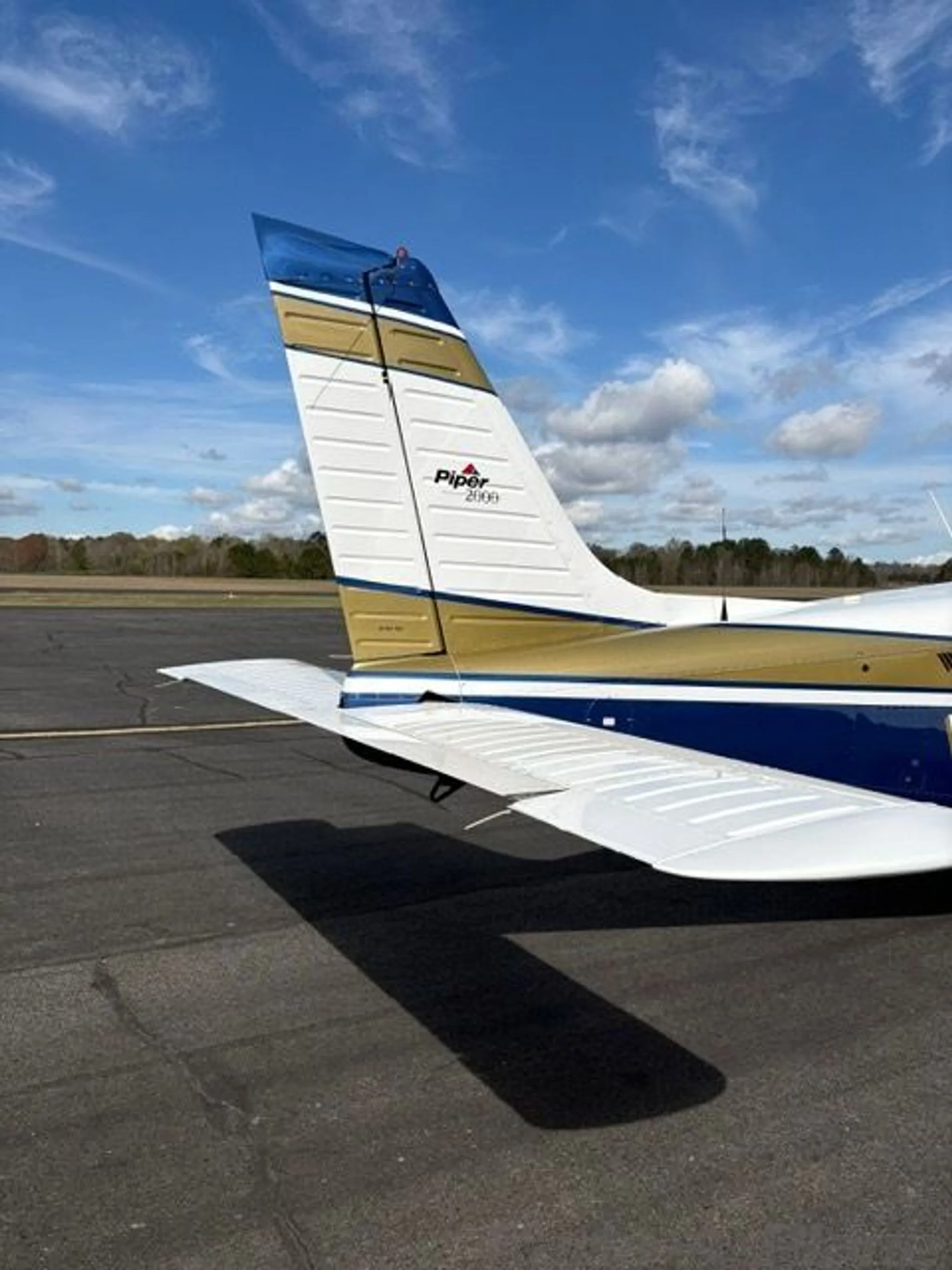 A close-up view of the tail section of the Piper Saratoga II TC, N4167N, featuring its white, blue, and gold paint scheme.