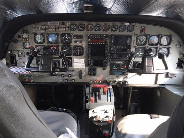 The cockpit of a Cessna Caravan aircraft, showing the instrument panel, yokes, and throttle quadrant.