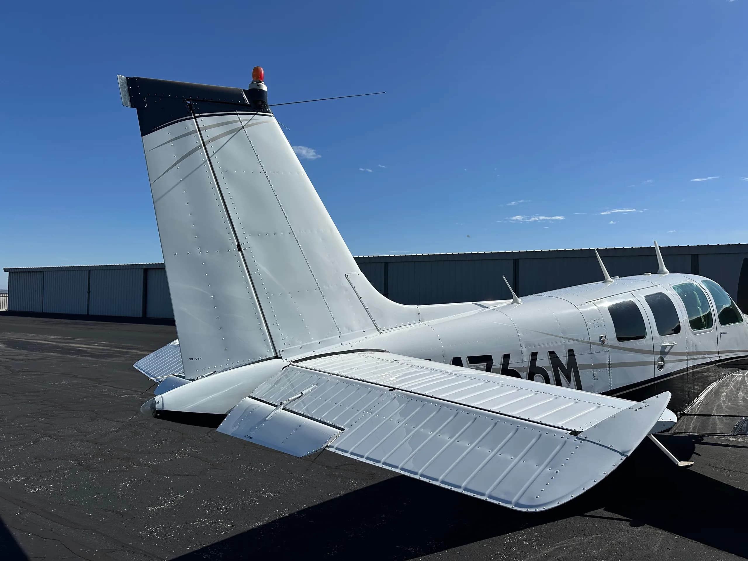 A Beechcraft Bonanza aircraft with registration N4766M is parked on the tarmac.