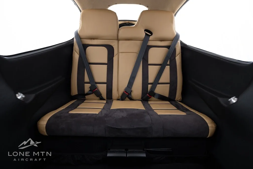 View of the tan and black rear cabin seats with seatbelts in a Cirrus SR22 aircraft.