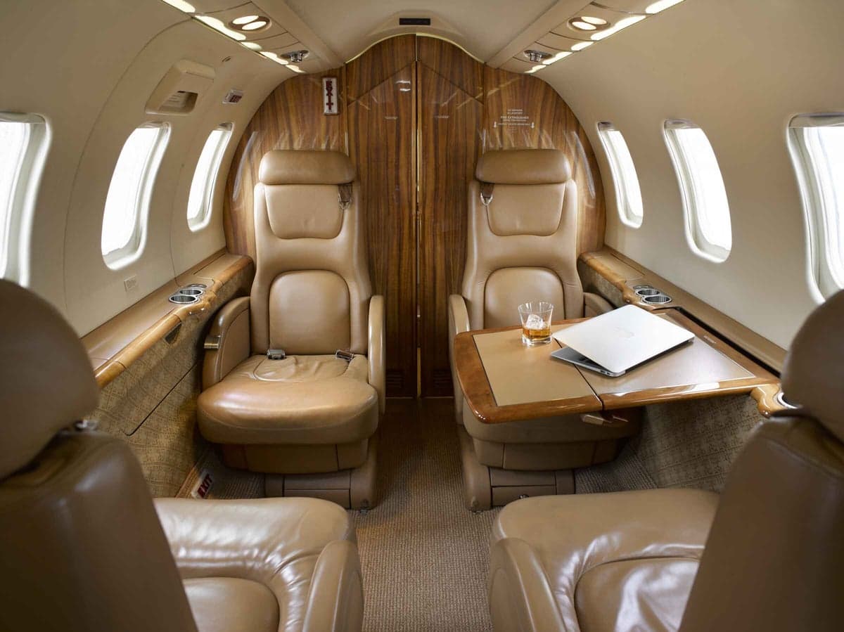 Interior view of the aircraft cabin with leather seats and a table.