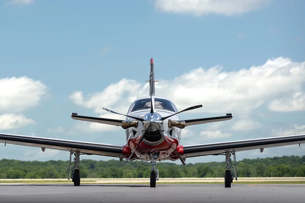 A head-on view of the white and red single-engine turboprop aircraft (TBM 850) with registration N580MD on a tarmac.