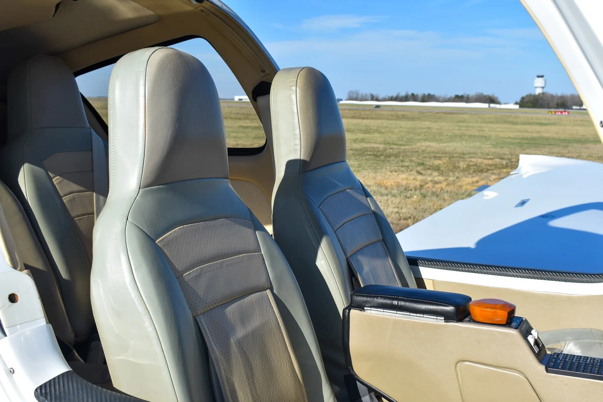 The light-colored leather seats of the aircraft's cabin, with a view of the airfield outside.