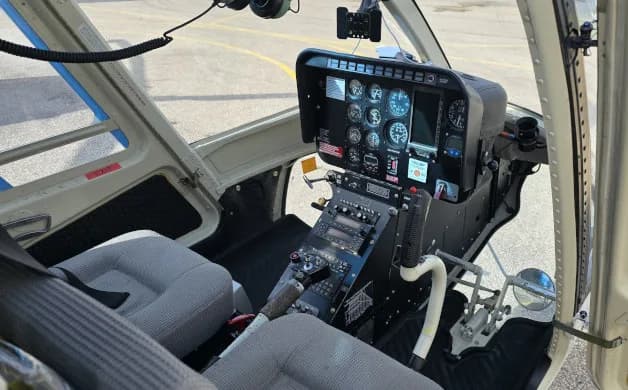 The cockpit of a helicopter features a control panel and seating.