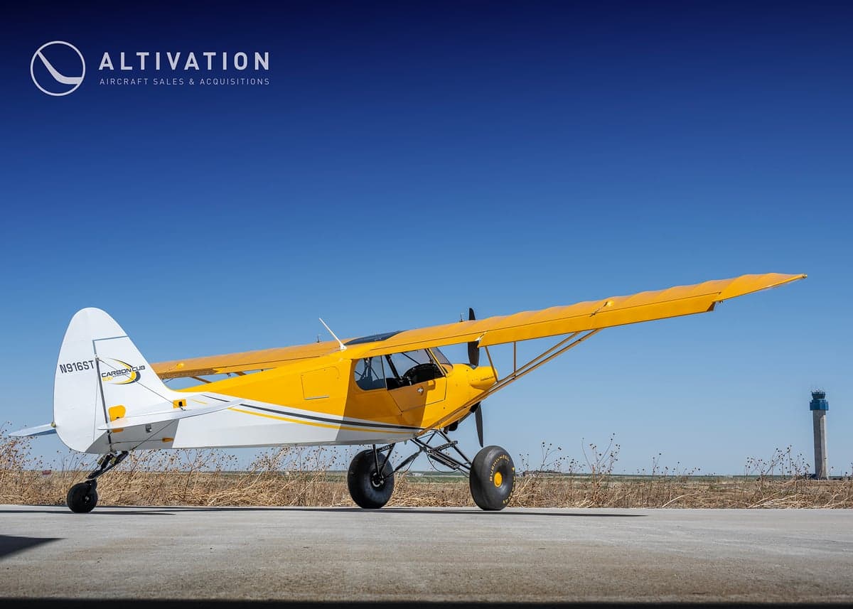 A yellow and white Carbon Cub aircraft parked on the tarmac.