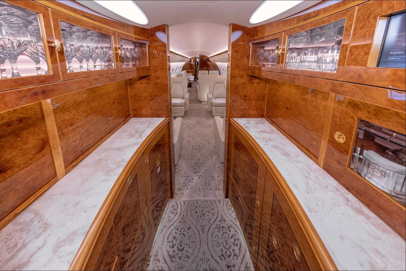 View of the aircraft's interior with wood cabinets and cream-colored seats.