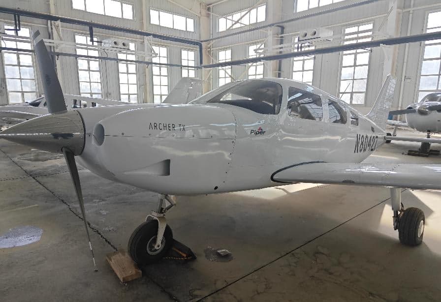 Front view of a Piper Archer TX aircraft, registration N80427, inside a hangar.