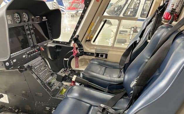 Interior view of the helicopter cabin with blue seats and a fire extinguisher.
