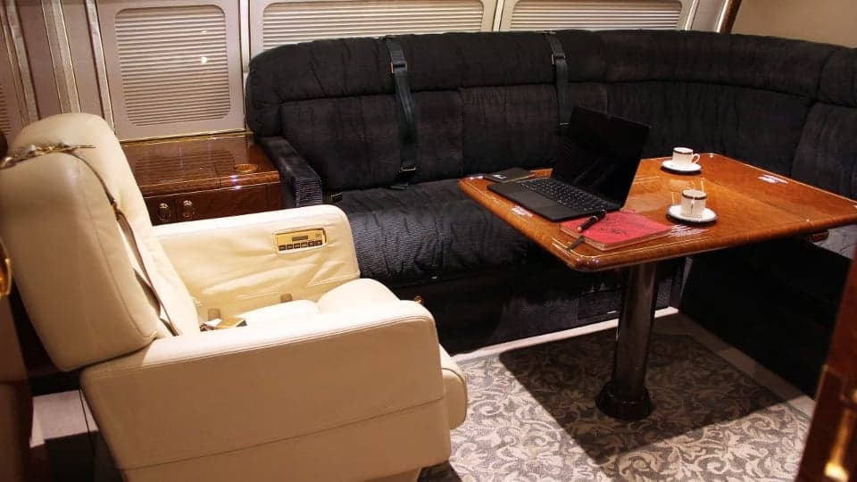 A comfortable seating area with a table and laptop inside the aircraft cabin.